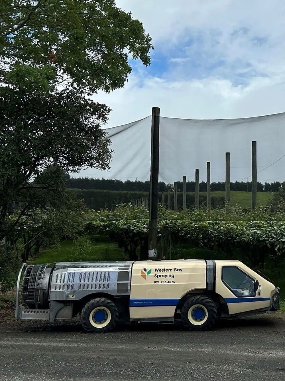 A Western Bay Spraying machine parked beside a kiwifruit block
